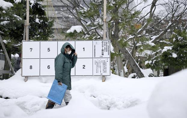 A person walks past a bulletin board for posters of candidates for the February 8 snap election, where snow has accumulated, in Fukui