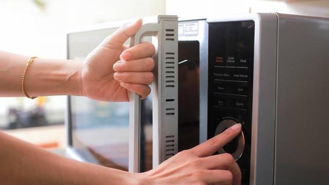 Woman's Hands Closing Microwave Oven Door And Preparing Food in 