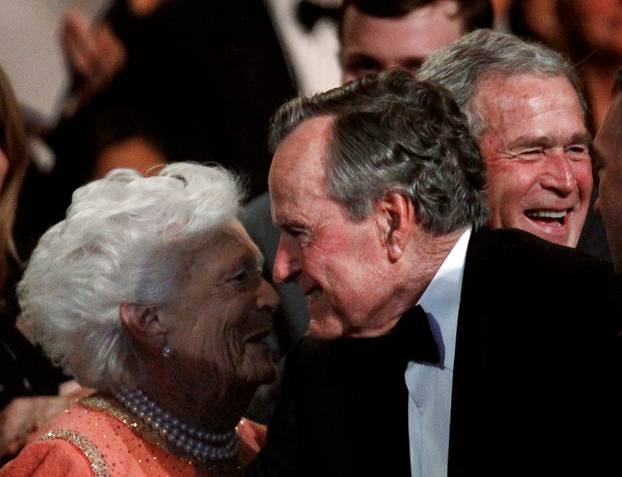 FILE PHOTO: Former U.S. President George. H.W. Bush (C) smiles at his wife Barbara (L), as their son former President George W. Bush (R) laughs in Washington