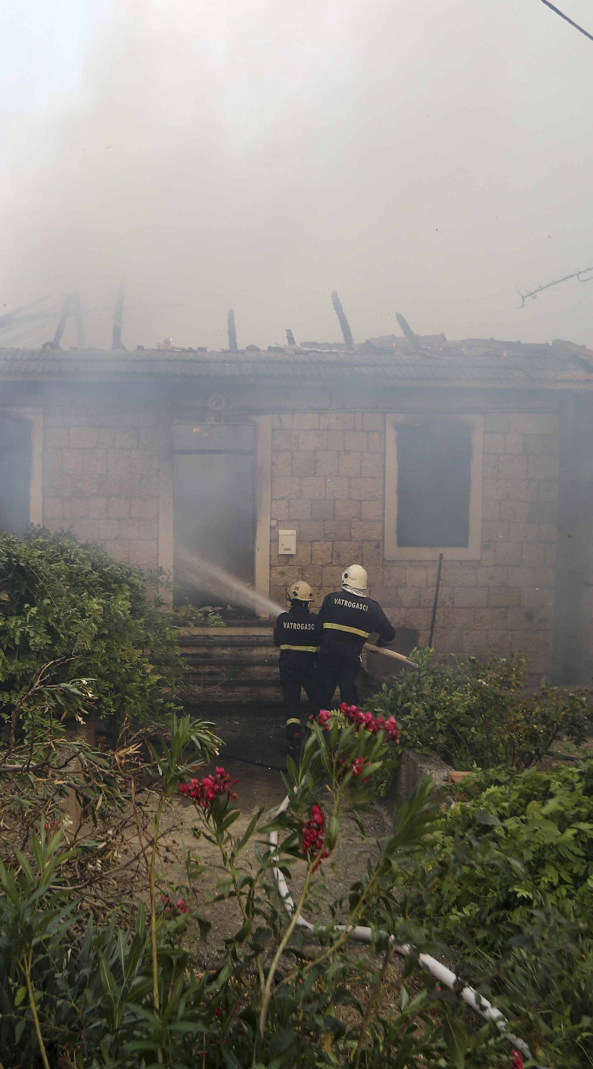 Firefighters try to extinguish a wildfire in the village of Mravince near Split
