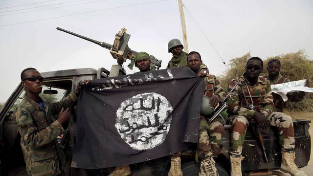 FILE PHOTO: Nigerian soldiers hold up a Boko Haram flag that they had seized in the recently retaken town of Damasak, Nigeria