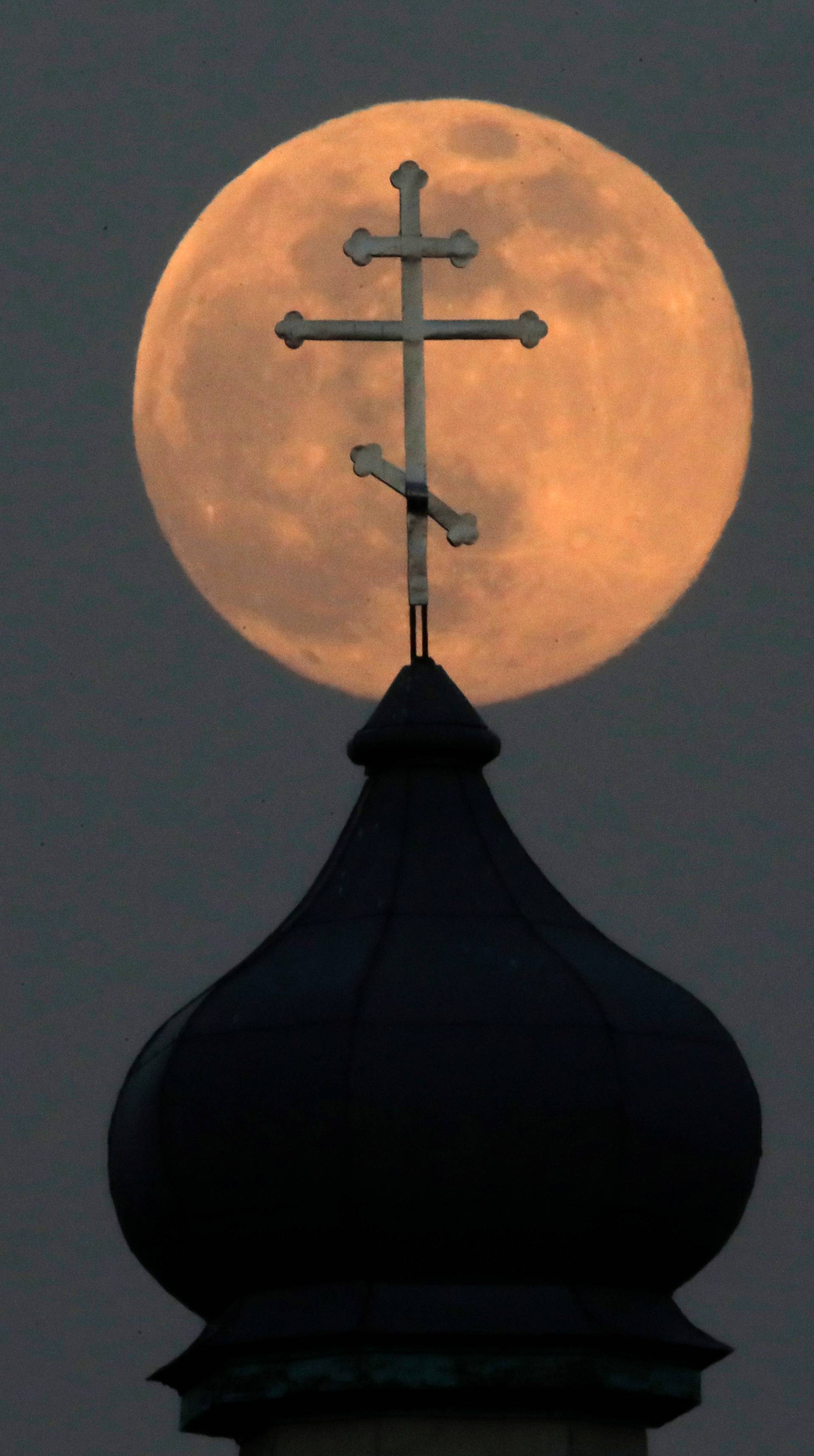 A Pink Supermoon rises behind an Orthodox Church in the village of Turets