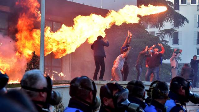 Flames are pictured behind a police formation during an anti-government protest in front of Prime Minister Edi Rama's office in Tirana