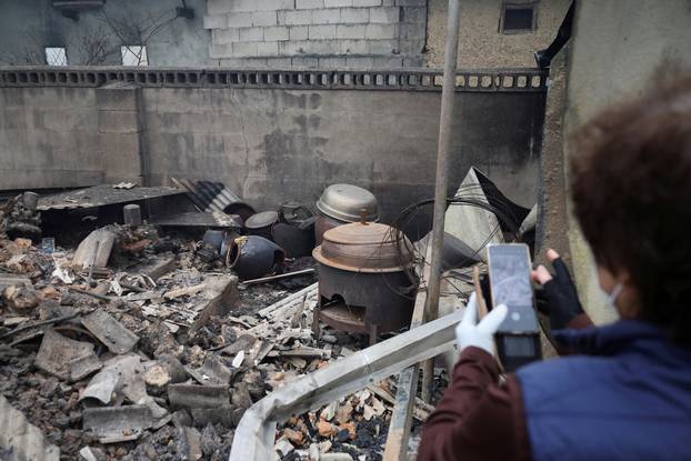 Kun Yeong-nam, 72, takes photographs on her mobile phone at her burnt house after a wildfire devastated the area in Uiseong