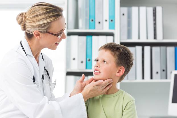 Pediatrician examining thyroid gland of boy