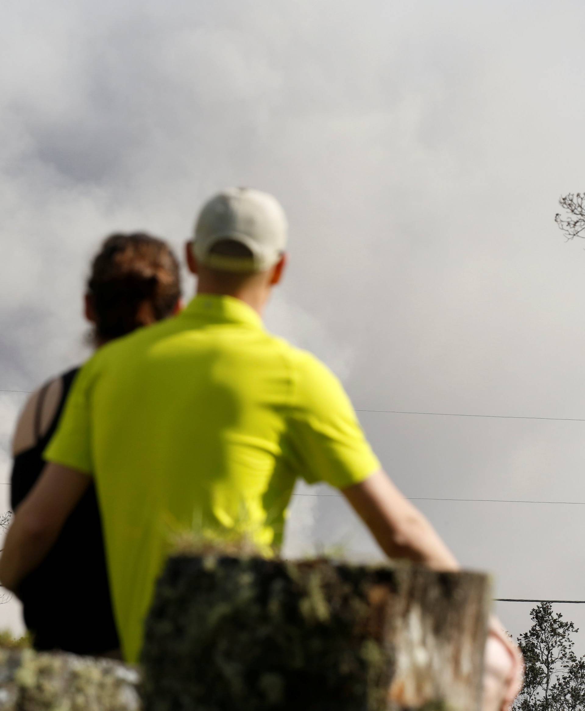 People watch ash erupt from Halemaumau Crater near the community of Volcano