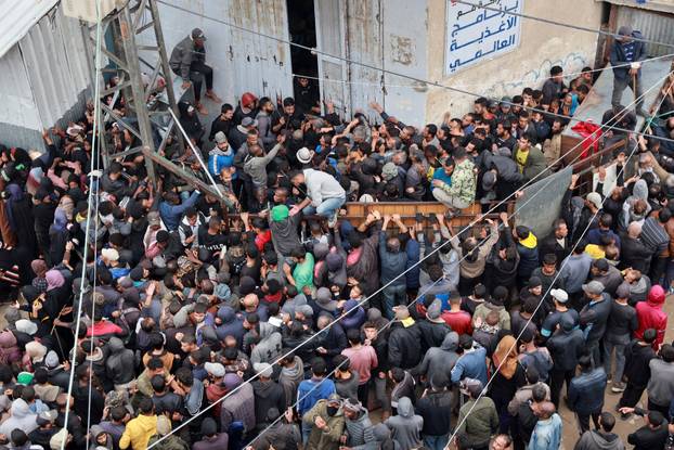 Palestinians gather to receive bread from a bakery in Deir Al-Balah