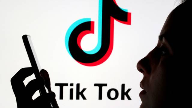 FILE PHOTO: A person holds a smartphone as Tik Tok logo is displayed behind in this picture illustration
