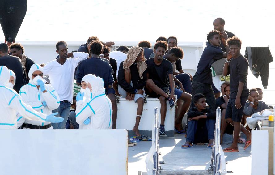 FILE PHOTO: Migrants wait to disembark from the Italian coast guard vessel "Diciotti" at the port of Catania