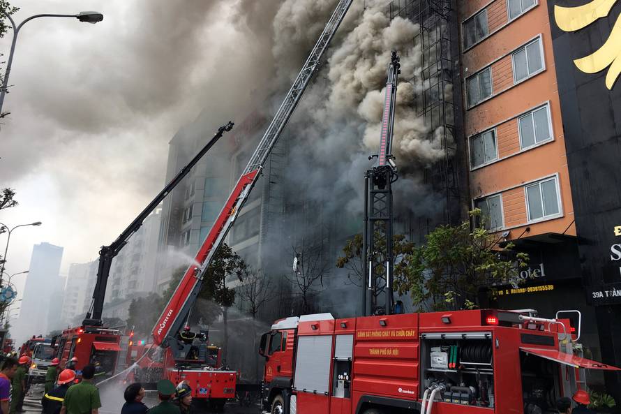 Firefighters work after a fire broke out at a karaoke lounge in Hanoi