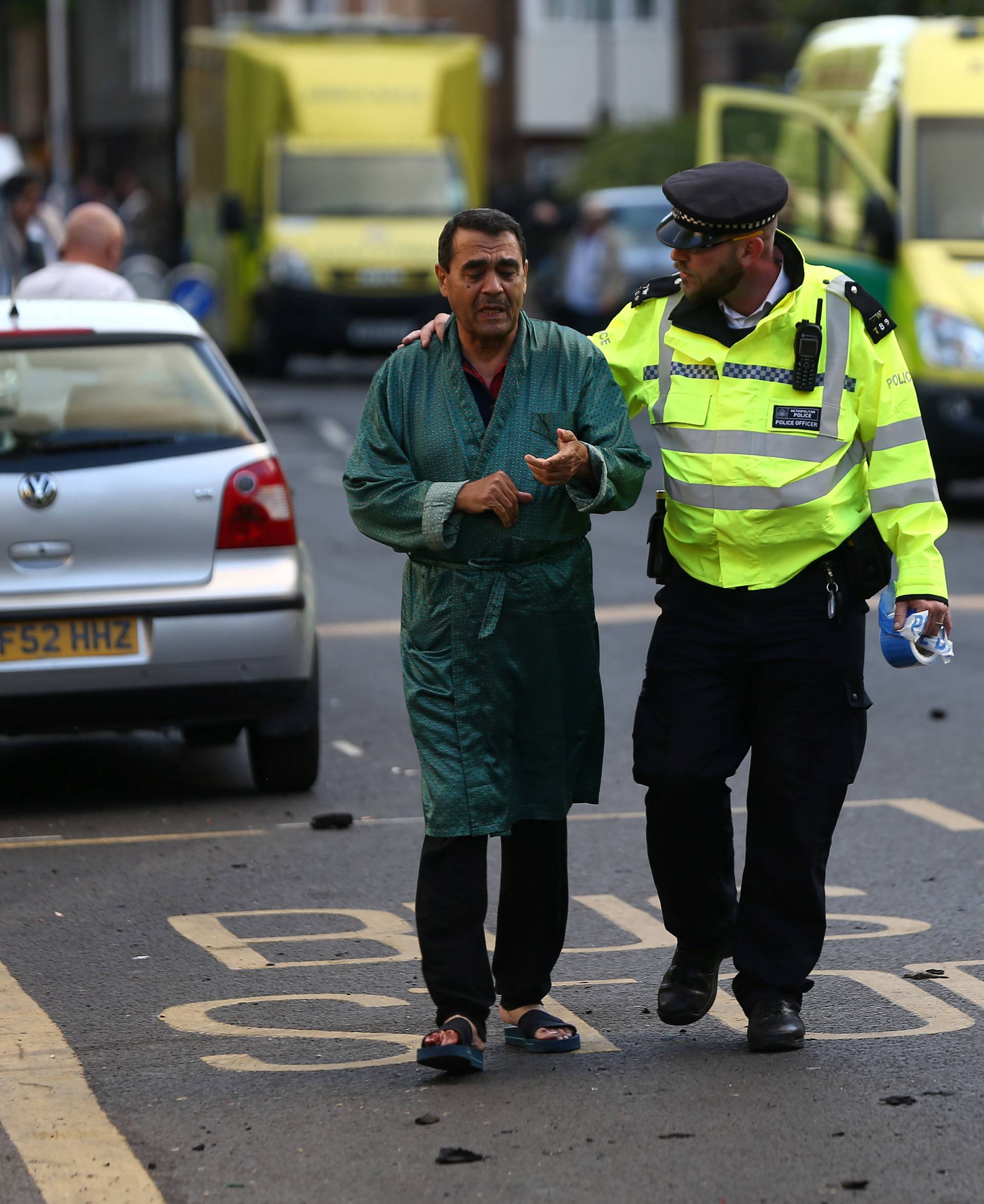 A police officer helps to evacuate a local resident from close to the scene of a serious fire in a tower block at Latimer Road in West London.