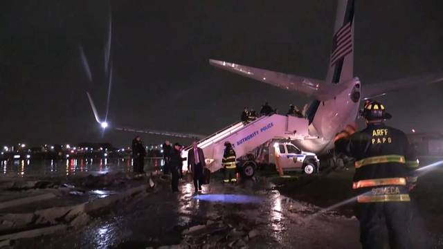 Still image of emergency workers standing in front of the plane carrying U.S. Republican vice presidential nominee Mike Pence after it skidded off the runway after landing in the rain at New York City's LaGuardia Airport