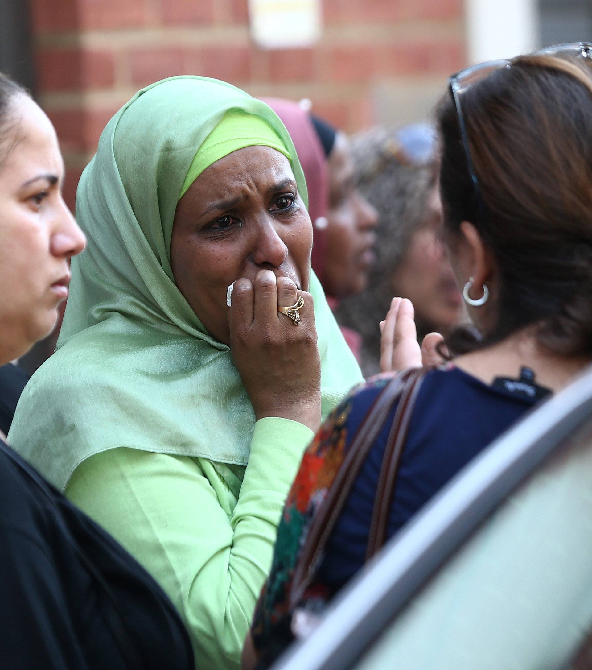 People react near a tower block severely damaged by a serious fire, in north Kensington, West London
