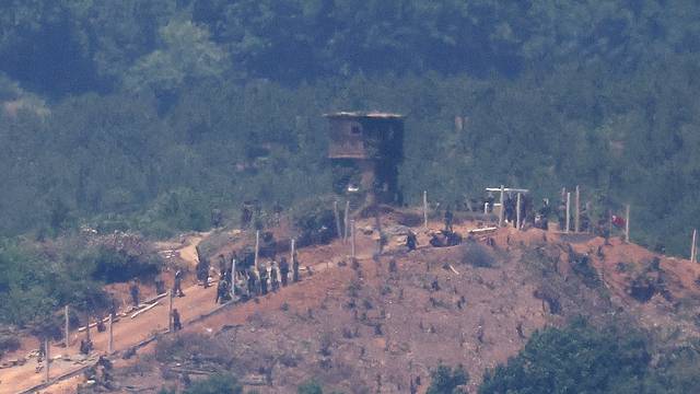 North Korean people work on a military fence near their guard post at the inter-Korean border