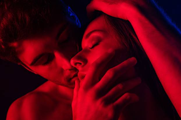 passionate undressed sexy man kissing woman in red light