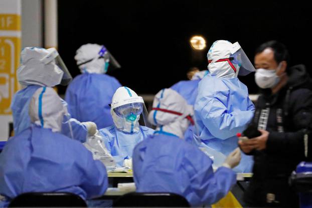 Workers in protective suits are seen at a makeshift nucleic acid testing site at Shanghai Pudong International Airport