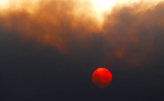 The sun sets behind the smoke of a forest fire in Arico