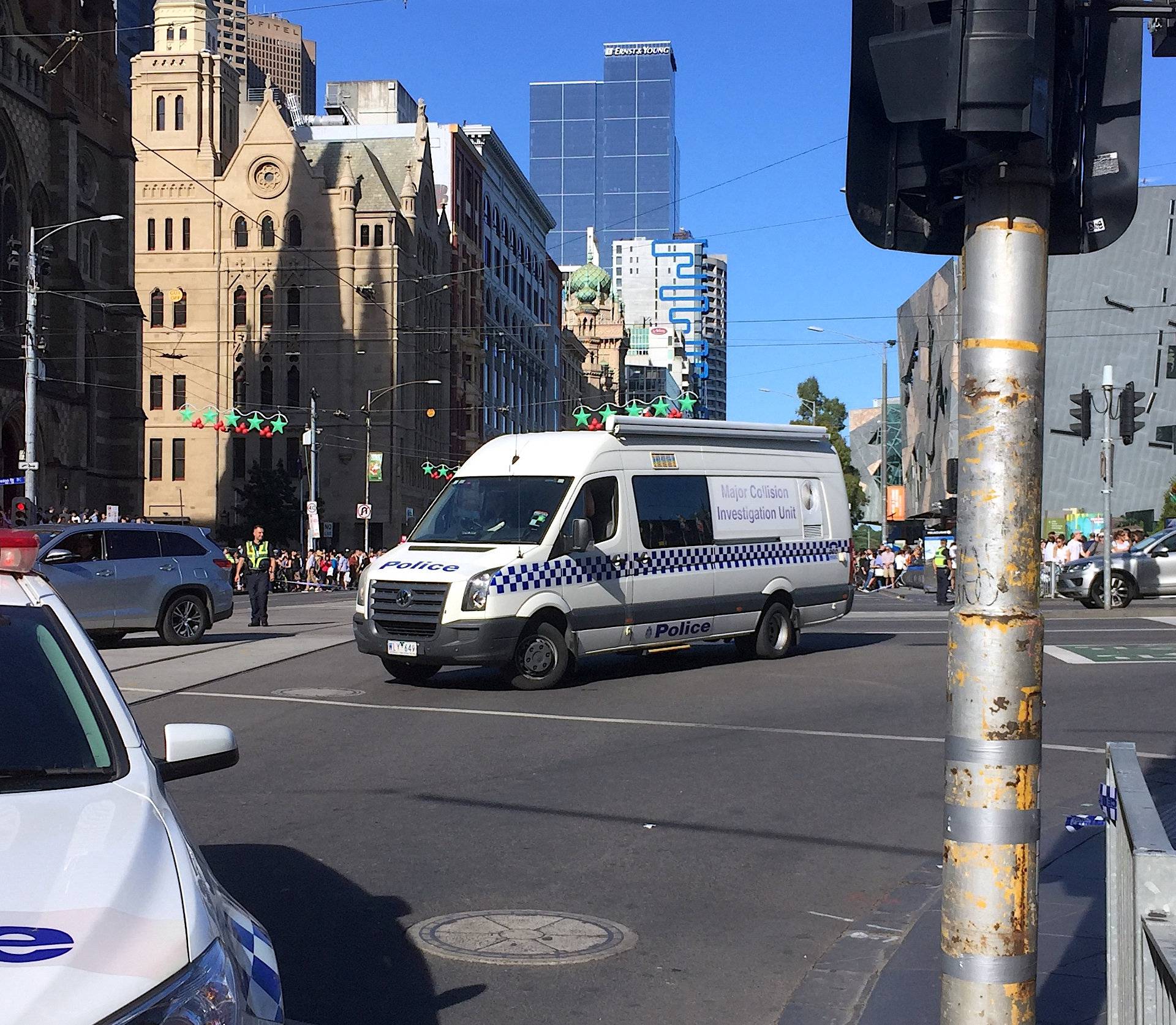 Members of the public stand behind police tape after Australian police said on Thursday they have arrested the driver of a vehicle that ploughed into pedestrians at a crowded intersection near the Flinders Street train station in central Melbourne