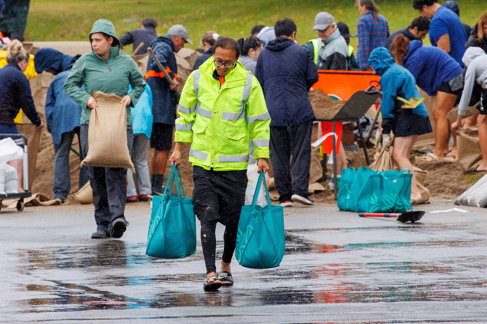 People fill up sandbags at a public collection point in preparation for the arrival of Cyclone Gabrielle in Auckland