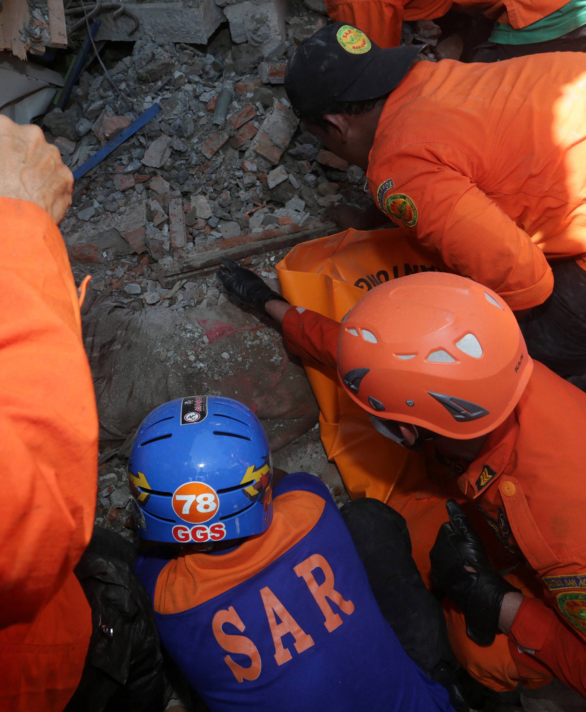 Rescue workers try to remove a victim from a collapsed building following an earthquake in Lueng Putu, Pidie Jaya in the northern province of Aceh, Indonesia