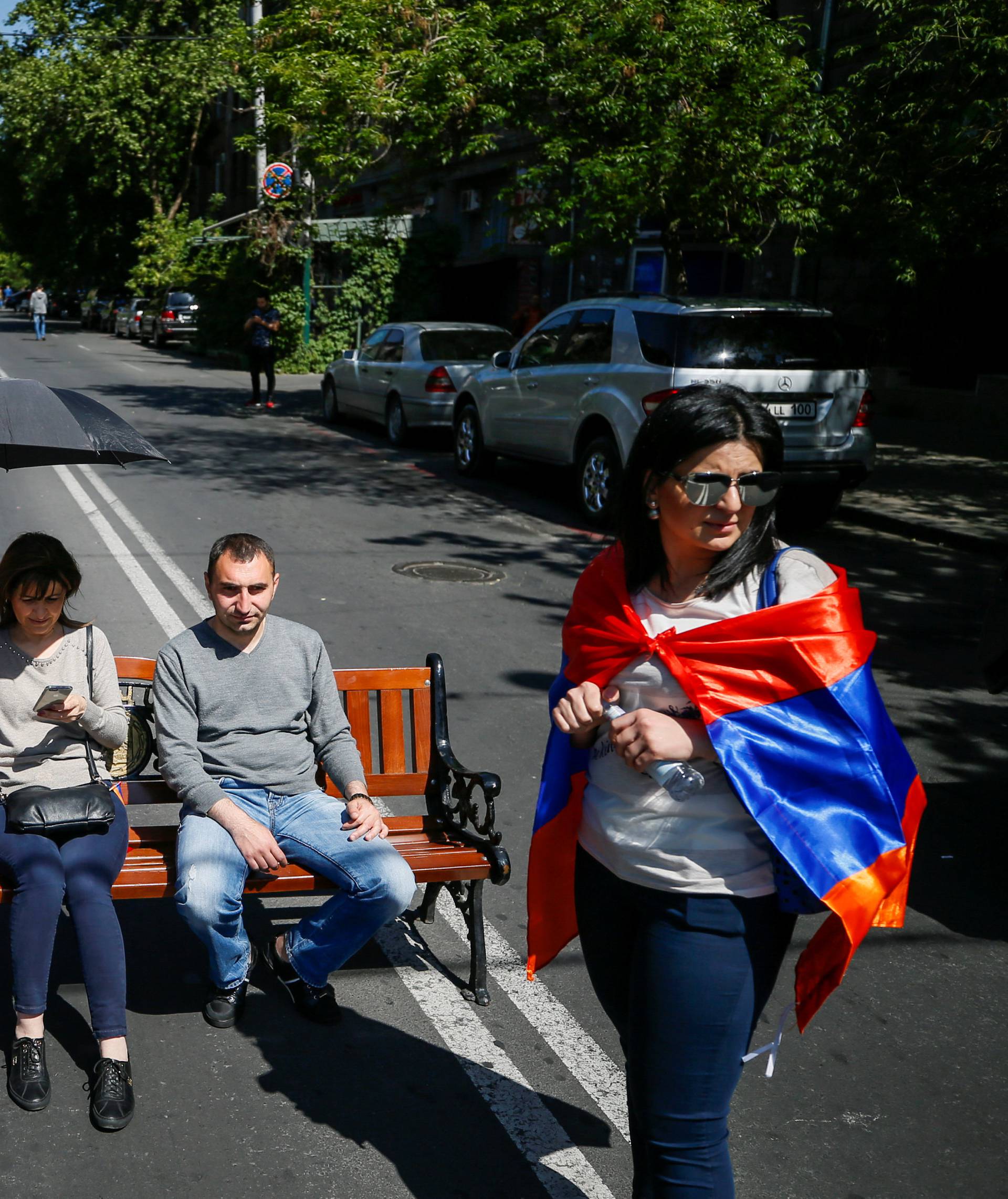 Armenian opposition supporters sit on bench as they block a road after protest movement leader Nikol Pashinyan announced a nationwide campaign of civil disobedience in Yerevan