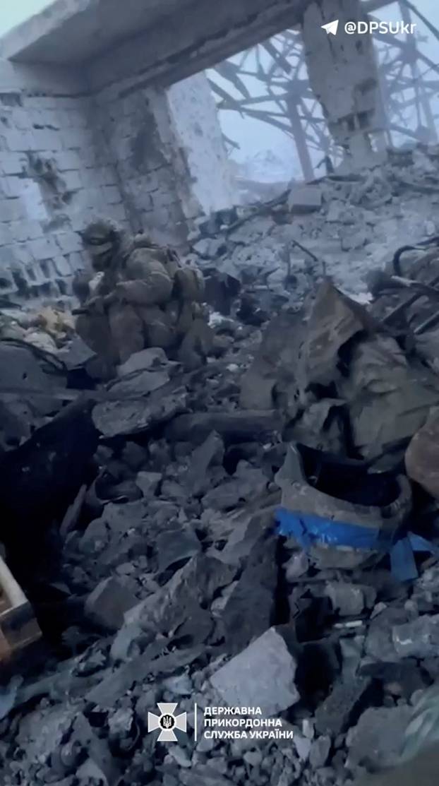 A Ukrainian soldier sits amid the rubble of a nearly destroyed building, in Avdiivka