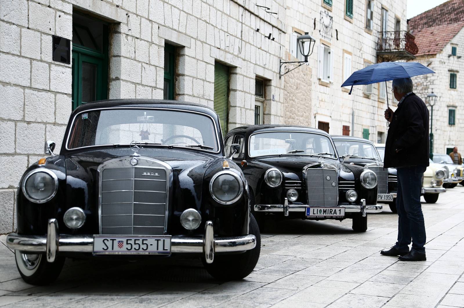 A man looks at old-timer Mercedes cars in Imotski