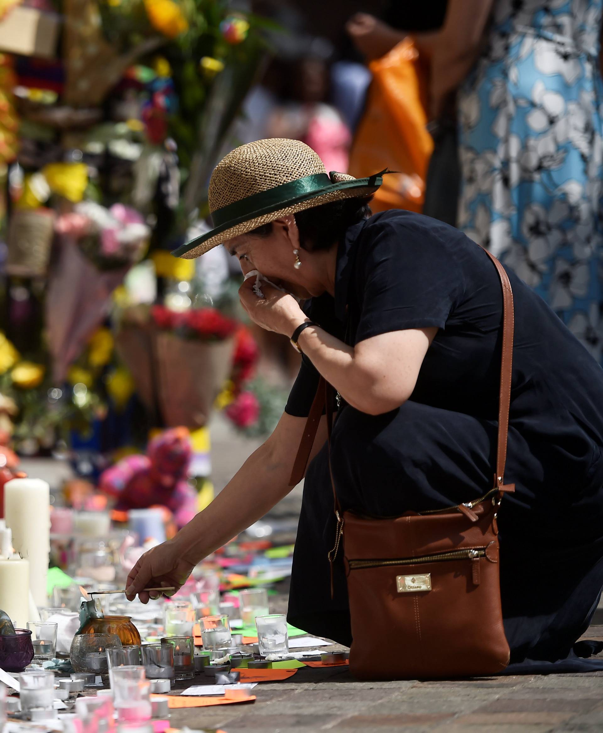 A woman lights a candle at a spot where people have left tributes to those who perished in the Grenfell apartment tower block fire in North Kensington, London