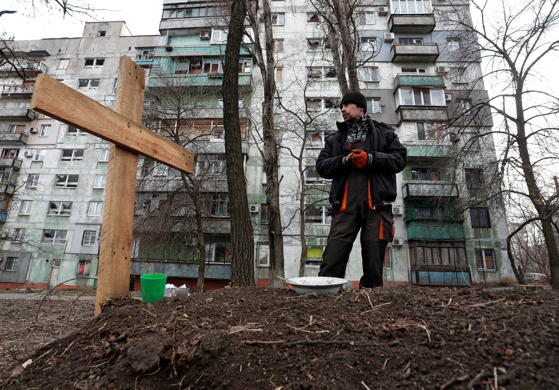 FILE PHOTO: A local resident stands next to the grave of his friend killed during Ukraine-Russia conflict in Mariupol