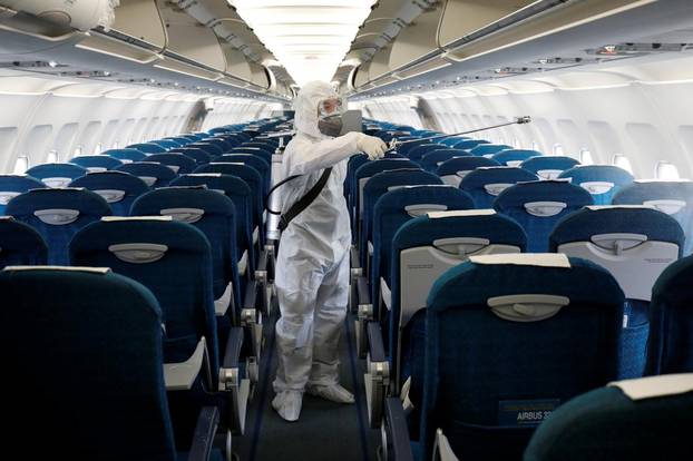 FILE PHOTO: A health worker sprays disinfectant inside a Vietnam Airlines airplane to protect against the recent coronavirus outbreak, at Noi Bai airport in Hanoi, Vietnam