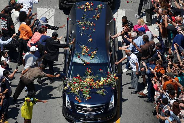 Well-wishers touch the hearse carrying the body of the late boxing champion Muhammad Ali during his funeral procession through Louisville, Kentucky