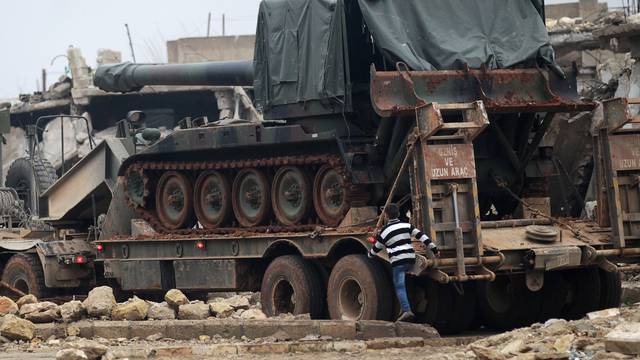 A boy walks past a Turkish tank mounted on a transporter in the northern Syrian rebel-held town of al-Rai