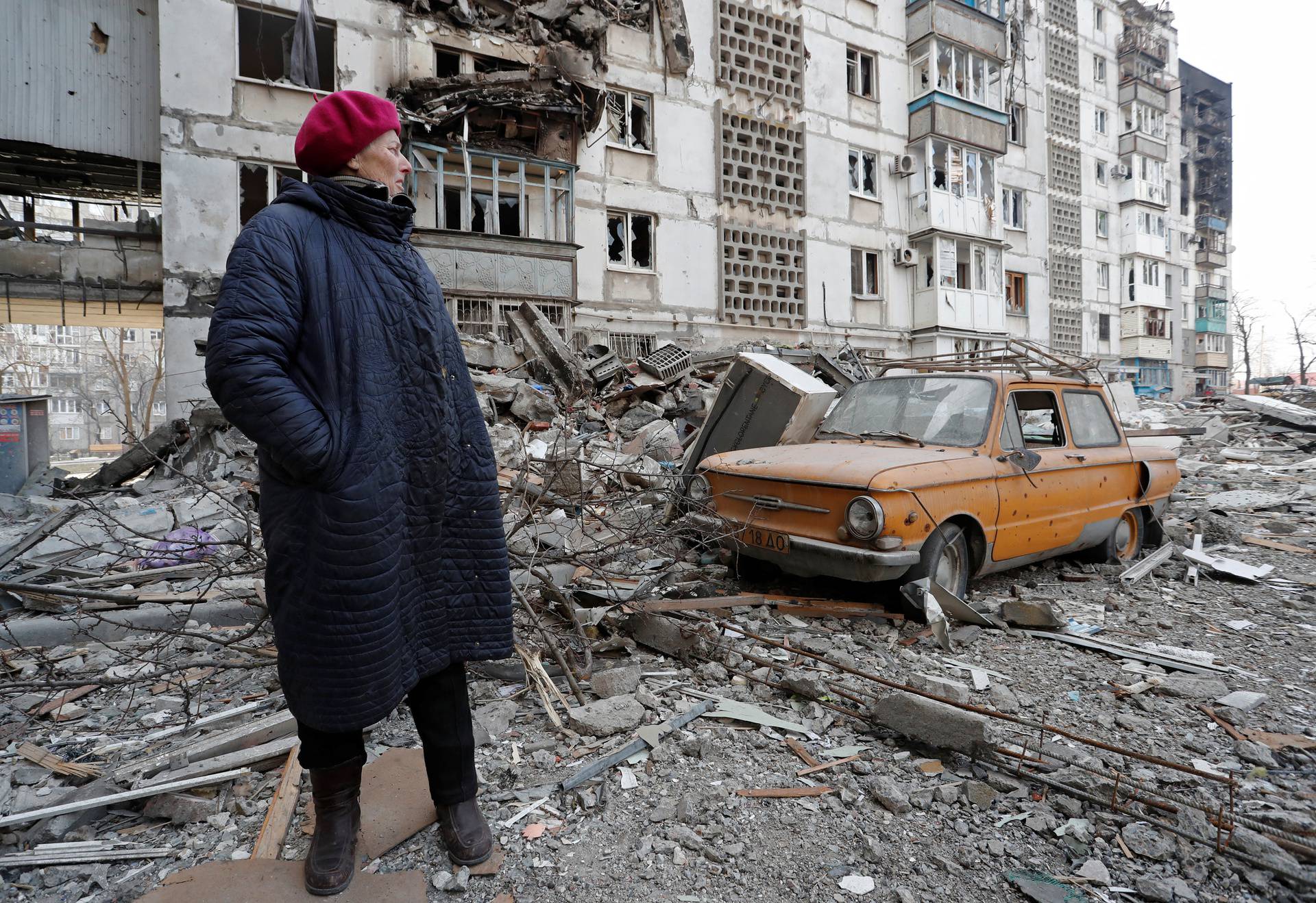 A local resident stands next to the building where her destroyed apartment is located in the besieged city of Mariupol