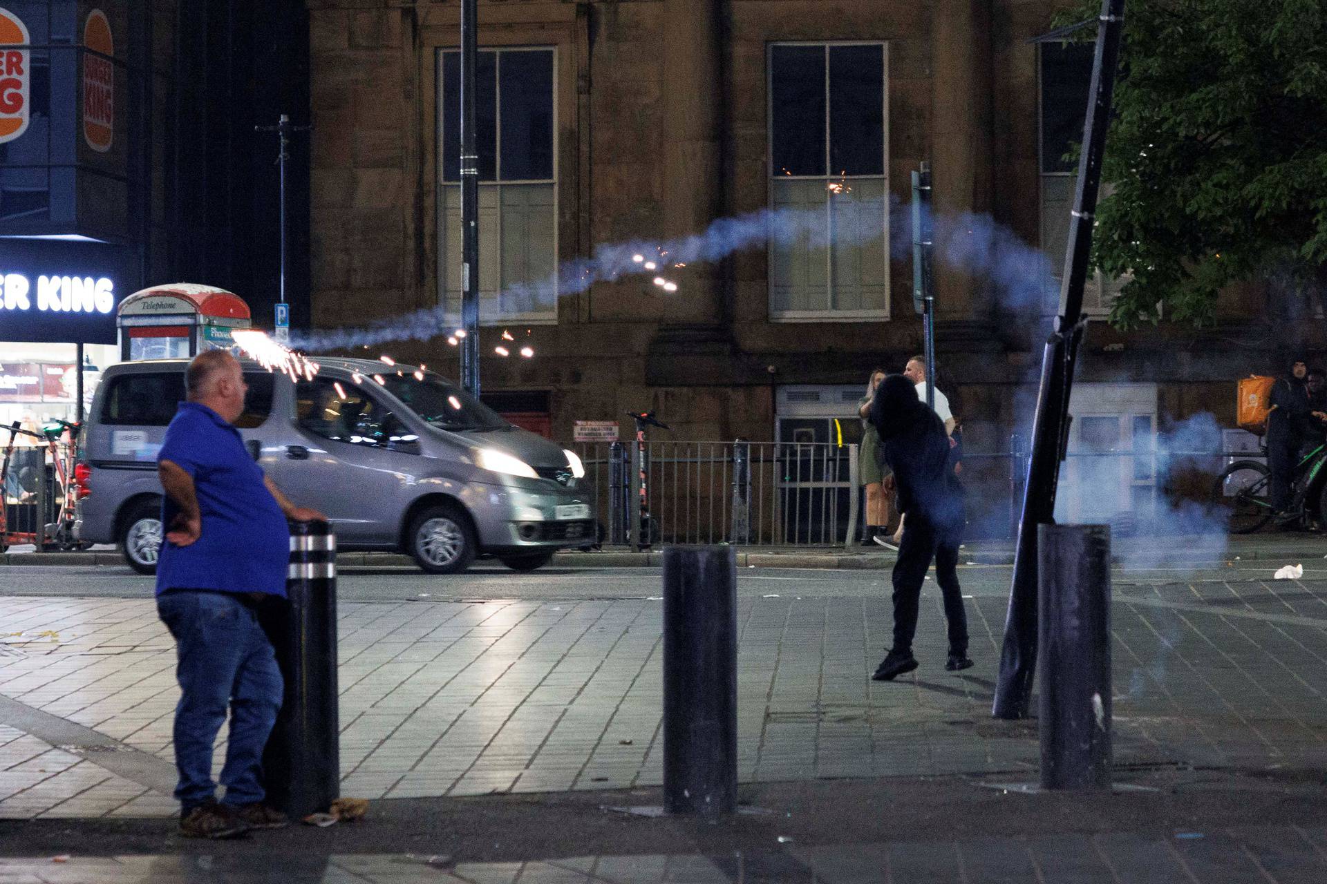 Protestors throw fireworks as the riots continue into the night in Liverpool,