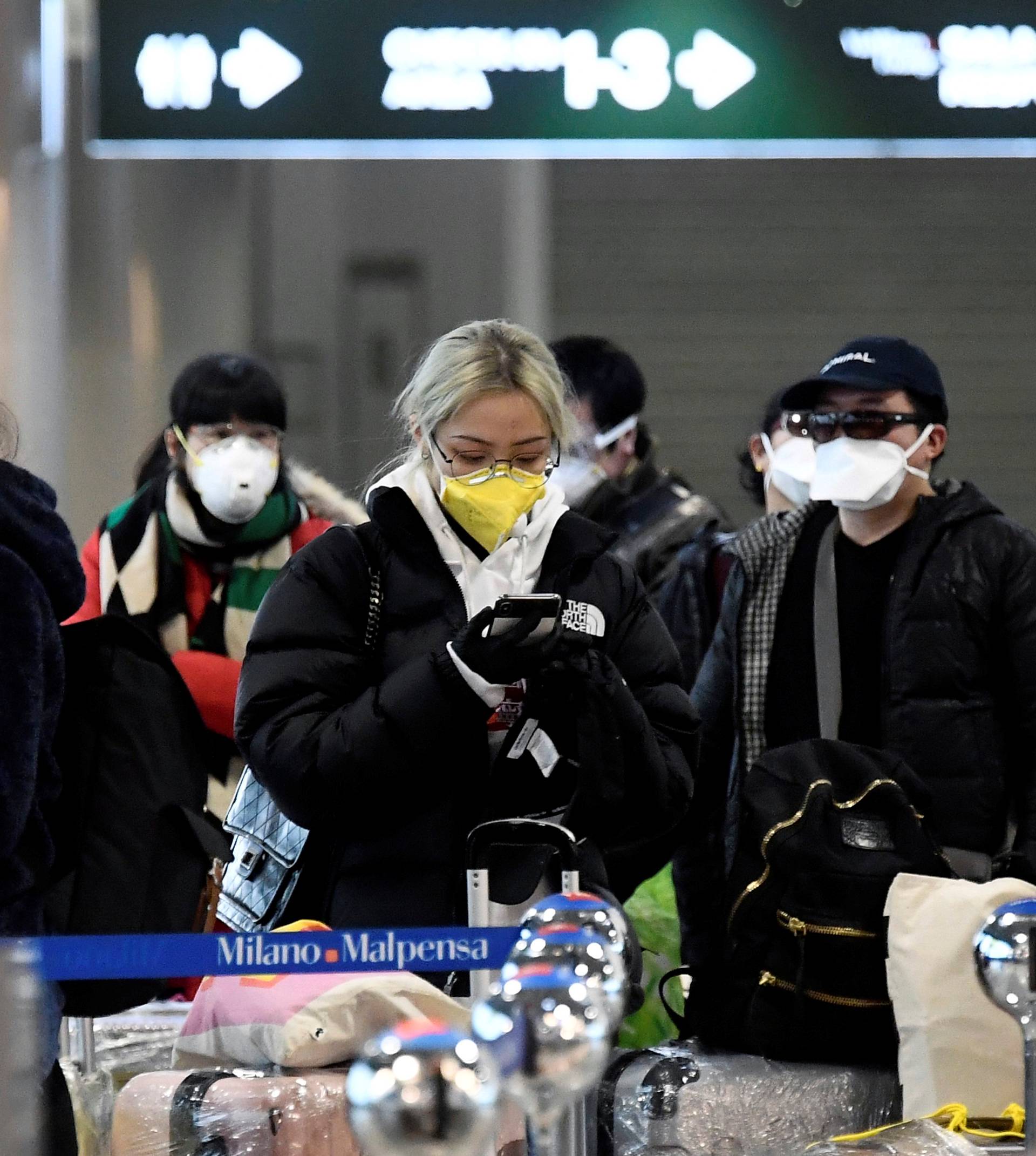 People wearing protective masks are seen at Malpensa airport near Milan