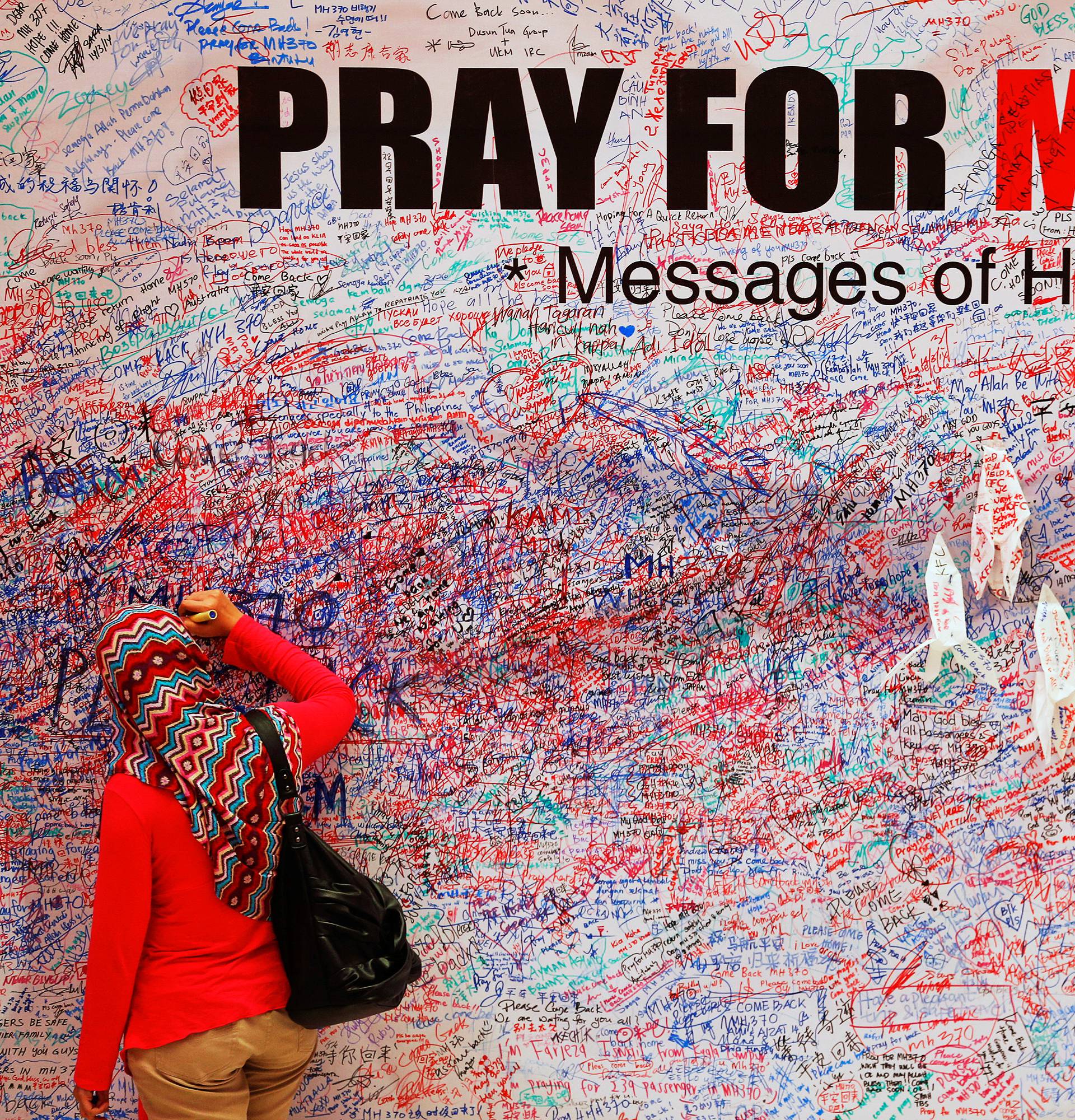 A woman leaves message of support and hope for passengers of missing Malaysia Airlines MH370 in central Kuala Lumpur