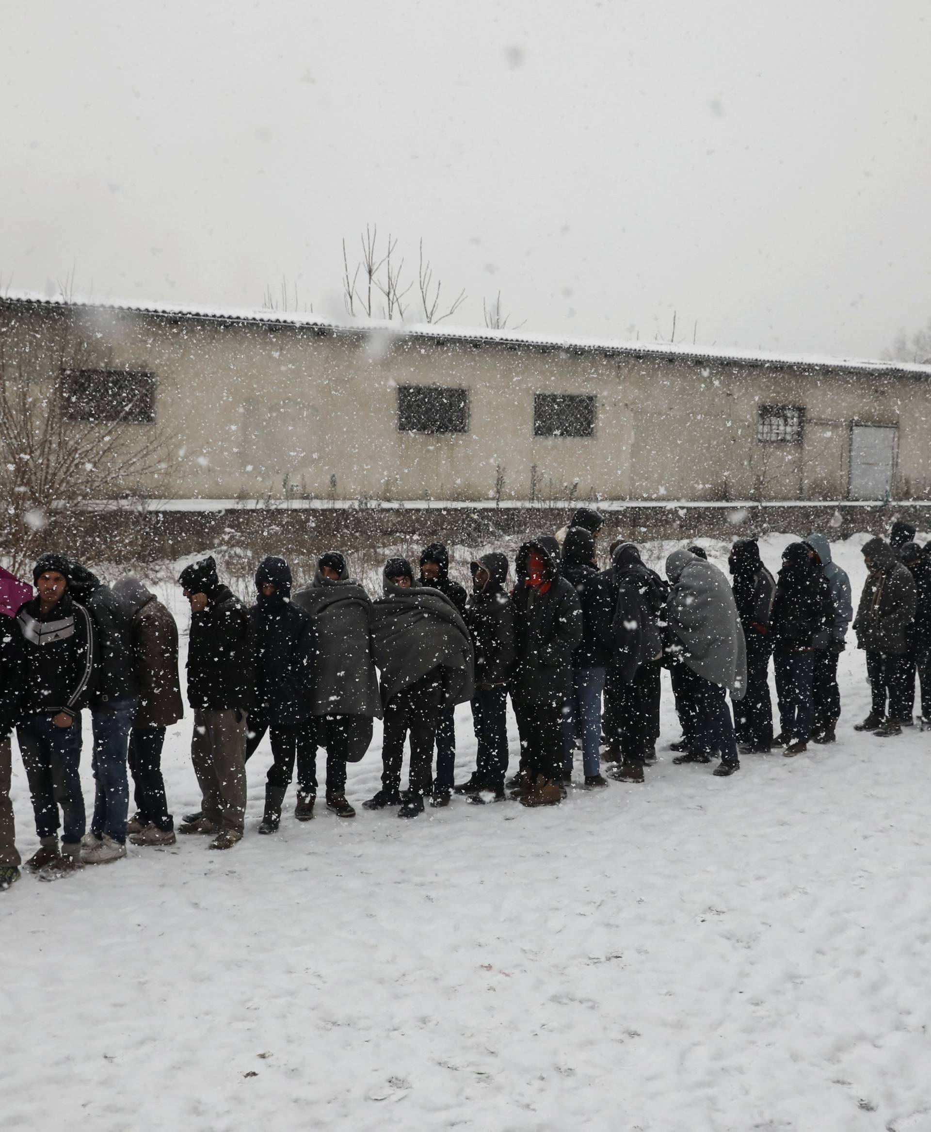 Migrants stand in line to receive free food outside a derelict customs warehouse in Belgrade