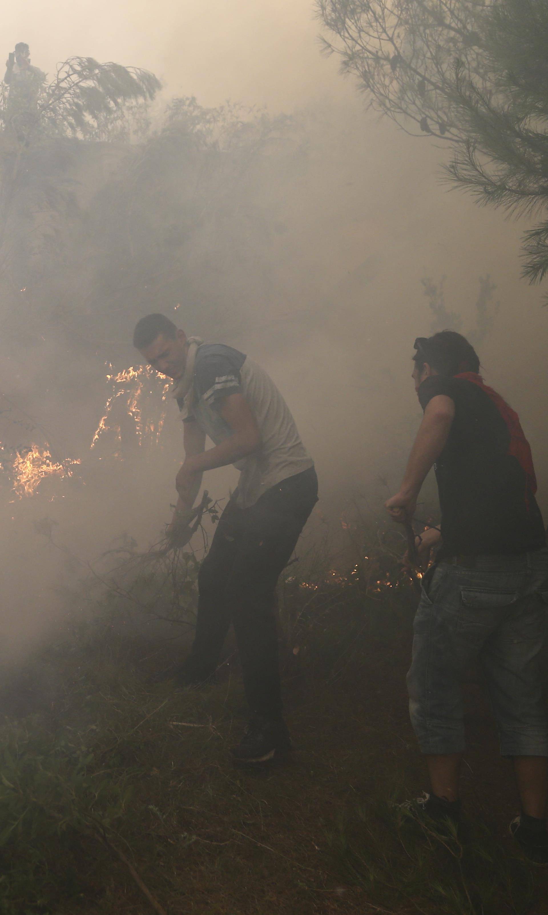 Local residents try to extinguish a wildfire in the village of Mravince near Split