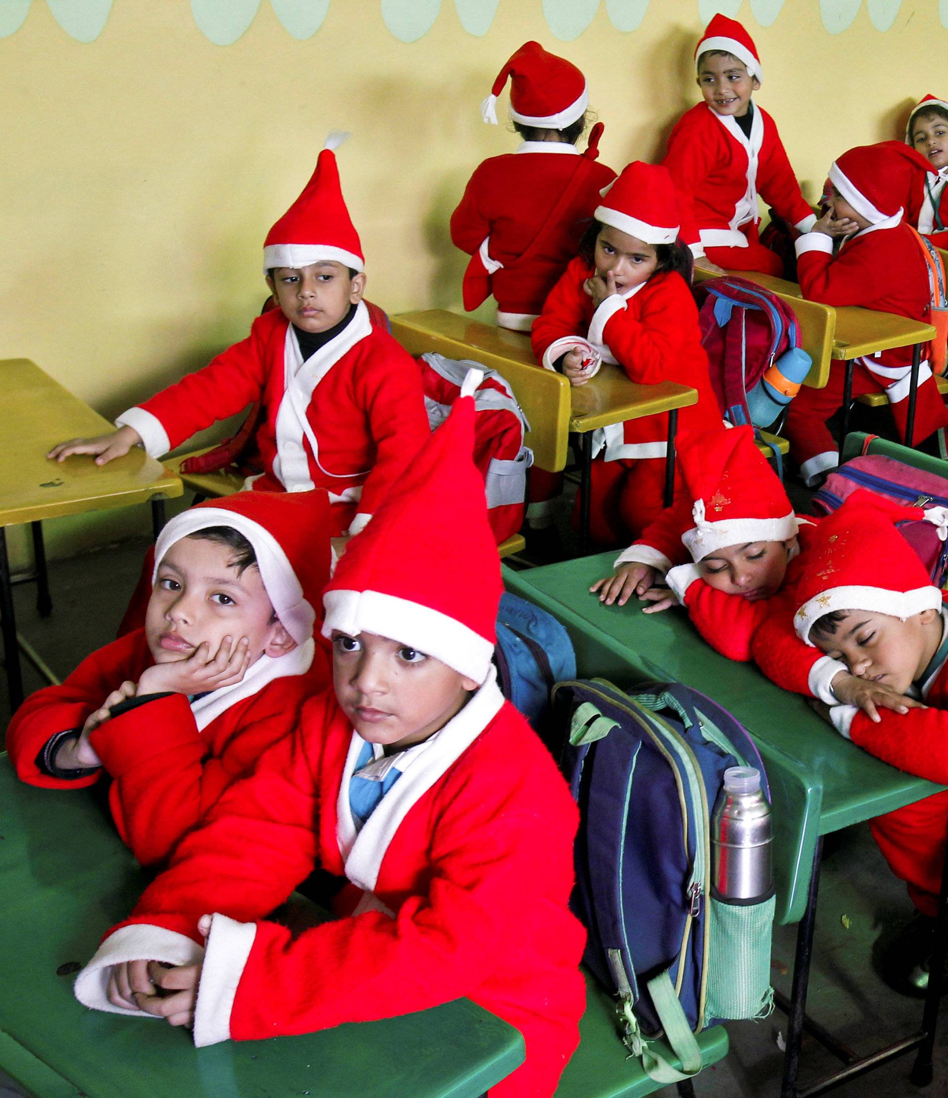 Children dressed in Santa Claus costumes sit inside a classroom before participating in Christmas celebrations at a school in Chandigarh