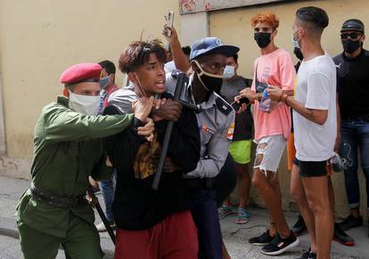 Police detain a person during protests against and in support of the government, in Havana