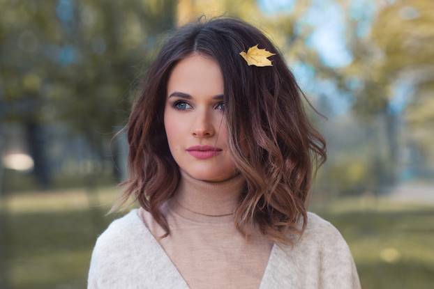 Perfect Woman with Yellow Autumn Leaf in Brown Hair Outdoors. Be