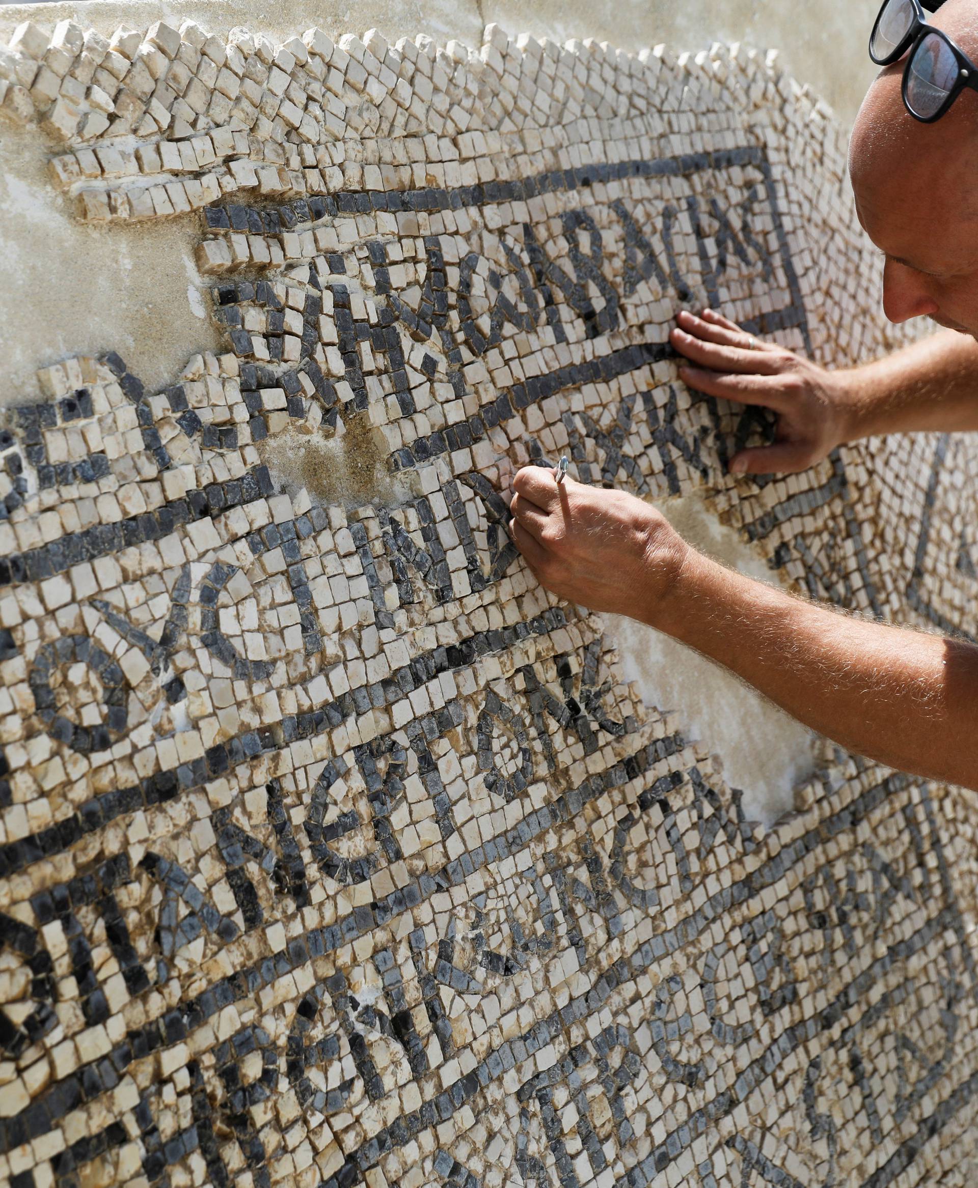 A conservationist works on a 1500-year-old mosaic floor bearing a Greek writing, discovered near Damascus Gate in Jerusalem's Old City, as it is displayed at the Rockefeller Museum in Jerusalem