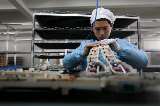 FILE PHOTO: Labourer works inside an electronics factory in Qingdao