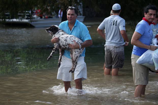 A man carries his dog through flood water after being evacuated from the rising water following Hurricane Harvey in a neighborhood west of Houston, Texas