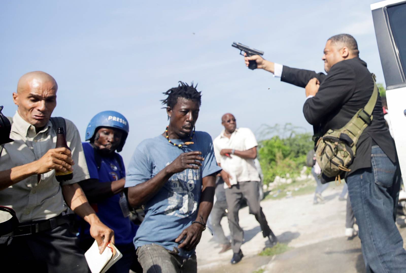 People run as Haiti's Senator Jean Marie Ralph Fethiere holds a gun in Port-au-Prince