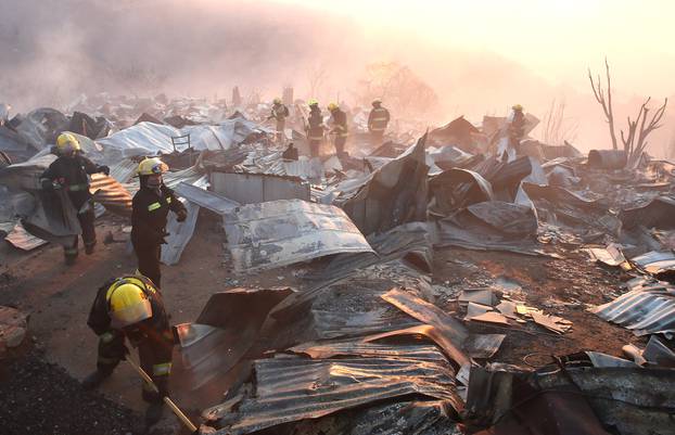 Firefighters remove the remains of a burned house on a hill, where more than 100 homes were burned due to forest fire but there have been no reports of death, local authorities said in Valparaiso, Chile