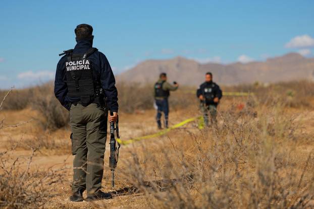A police stands guard at a scene where human remains were found in Ciudad Juarez