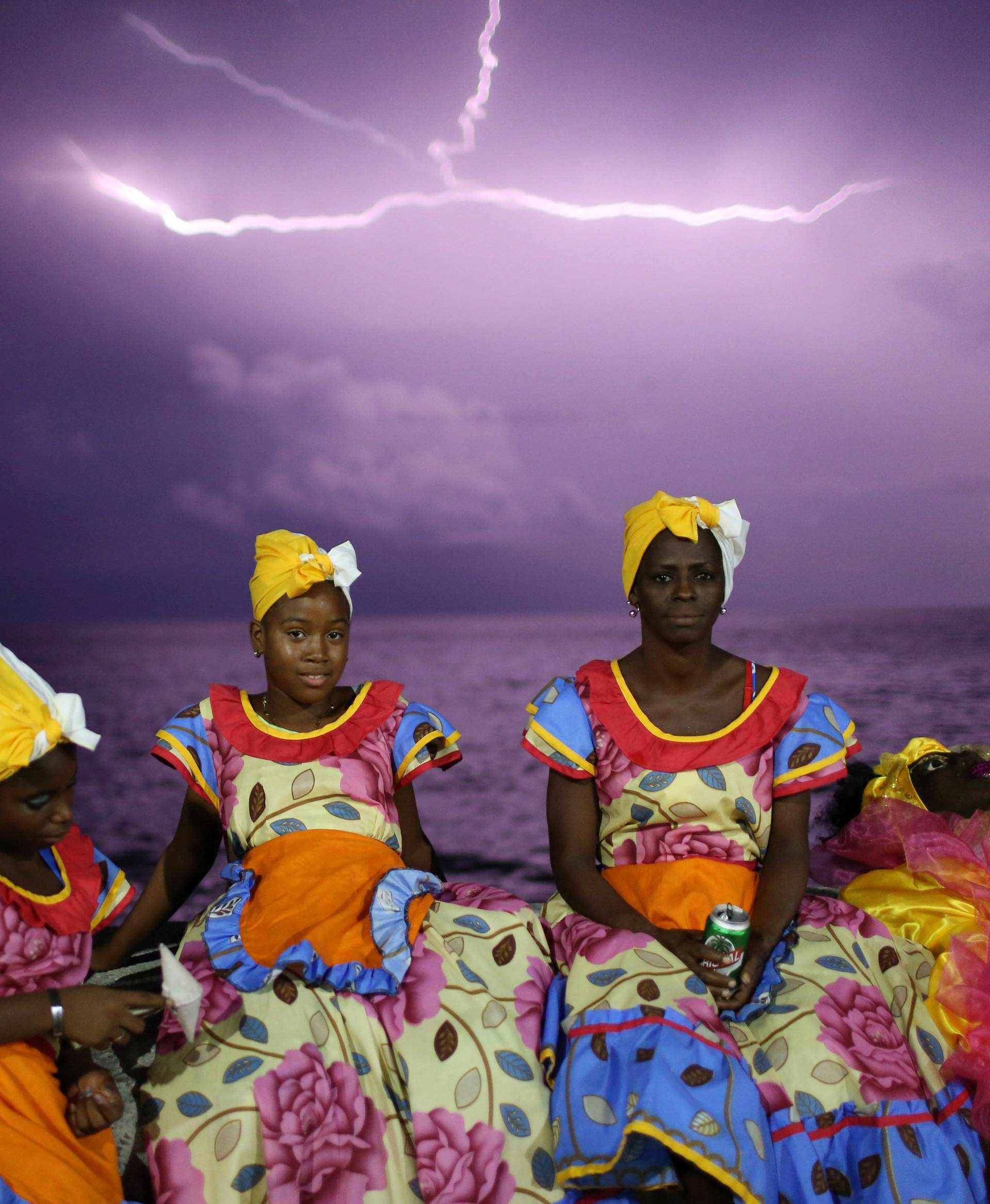 Revellers chat on Havana's Malecon seafront before performing at a carnival parade, Cuba