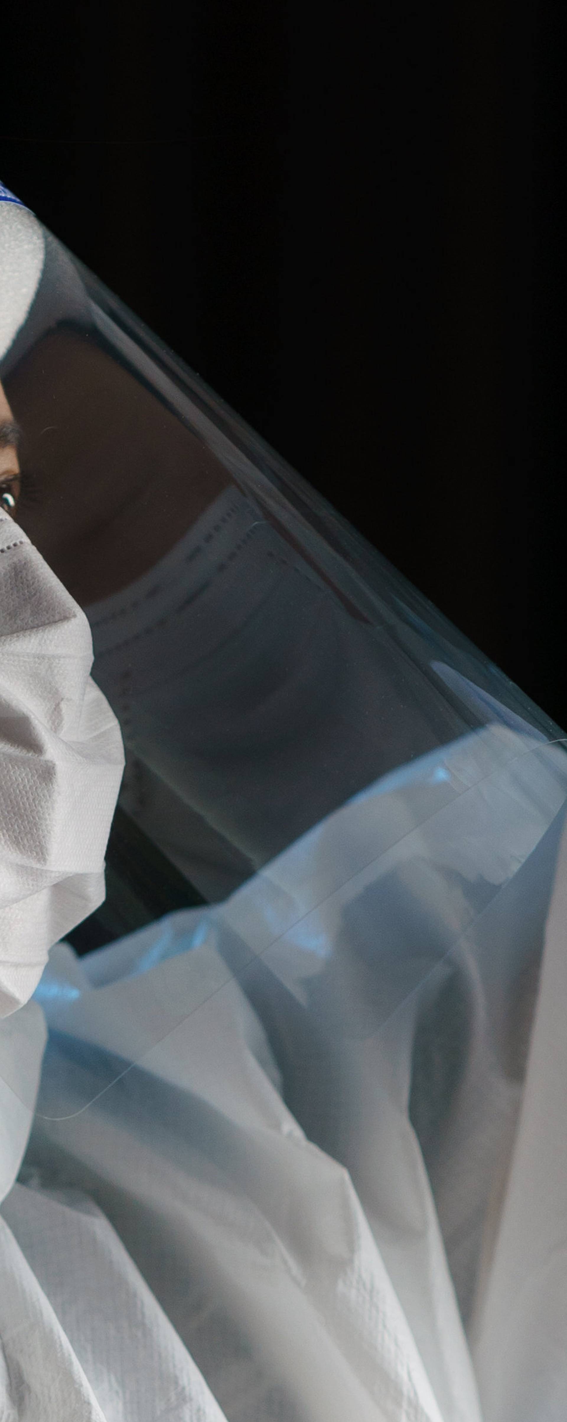 Woman wearing gloves, biohazard protective suit, face shield and