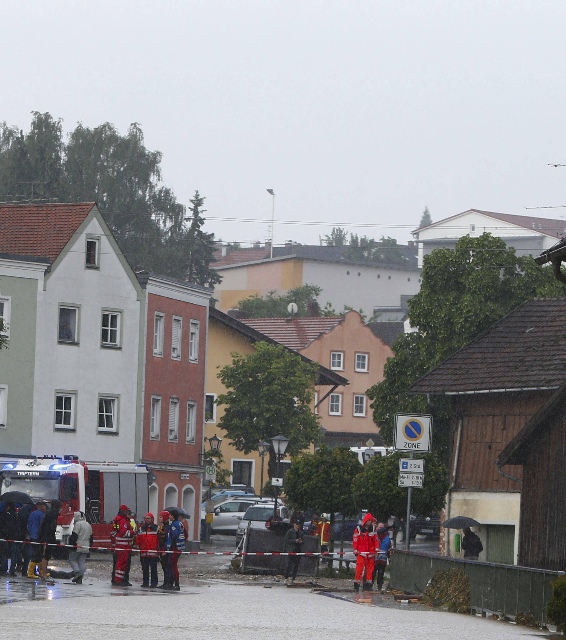 Local residents and firefighters stand in the flooded street in the Bavarian village of Triftern